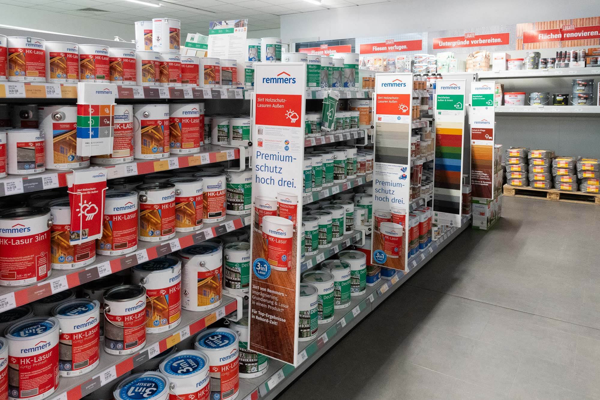 Regal im Baumarkt mit Dosen für Holzschutzlasuren und Farben in verschiedenen Größen.