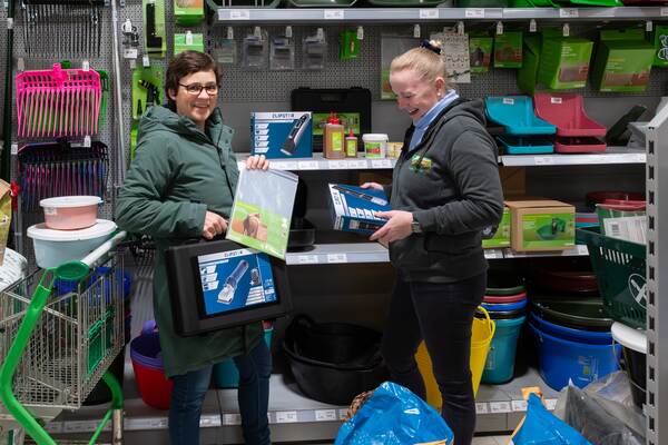 Zwei Frauen in einer Reitsportabteilung begutachten eine Schermaschine für Pferde und lächeln dabei.