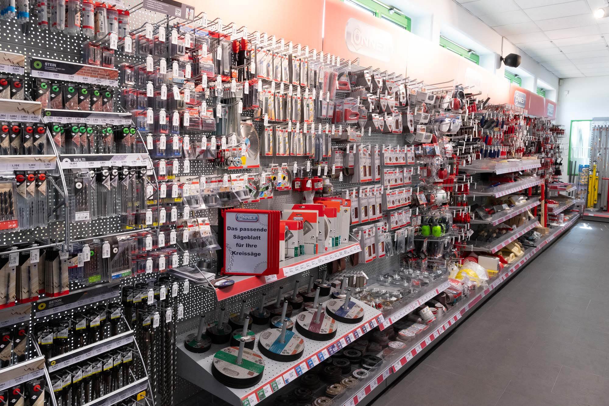 Regalwand in einem Baumarkt mit Bohrern, Sägeblättern, Schleifscheiben und weiterem Werkzeugzubehör.