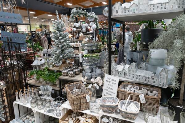 Du siehst weihnachtliche Dekorationen mit Kunstschnee, Kerzen, Dekofiguren und kleinen Häusern.