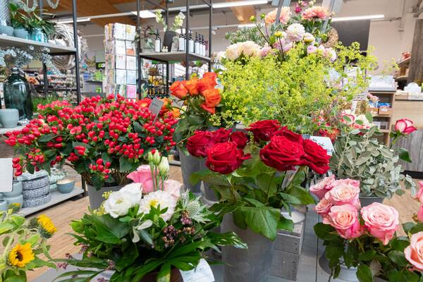Du siehst eine bunte Auswahl an frischen Schnittblumen im Raiffeisen-Markt, darunter Rosen und Beeren.